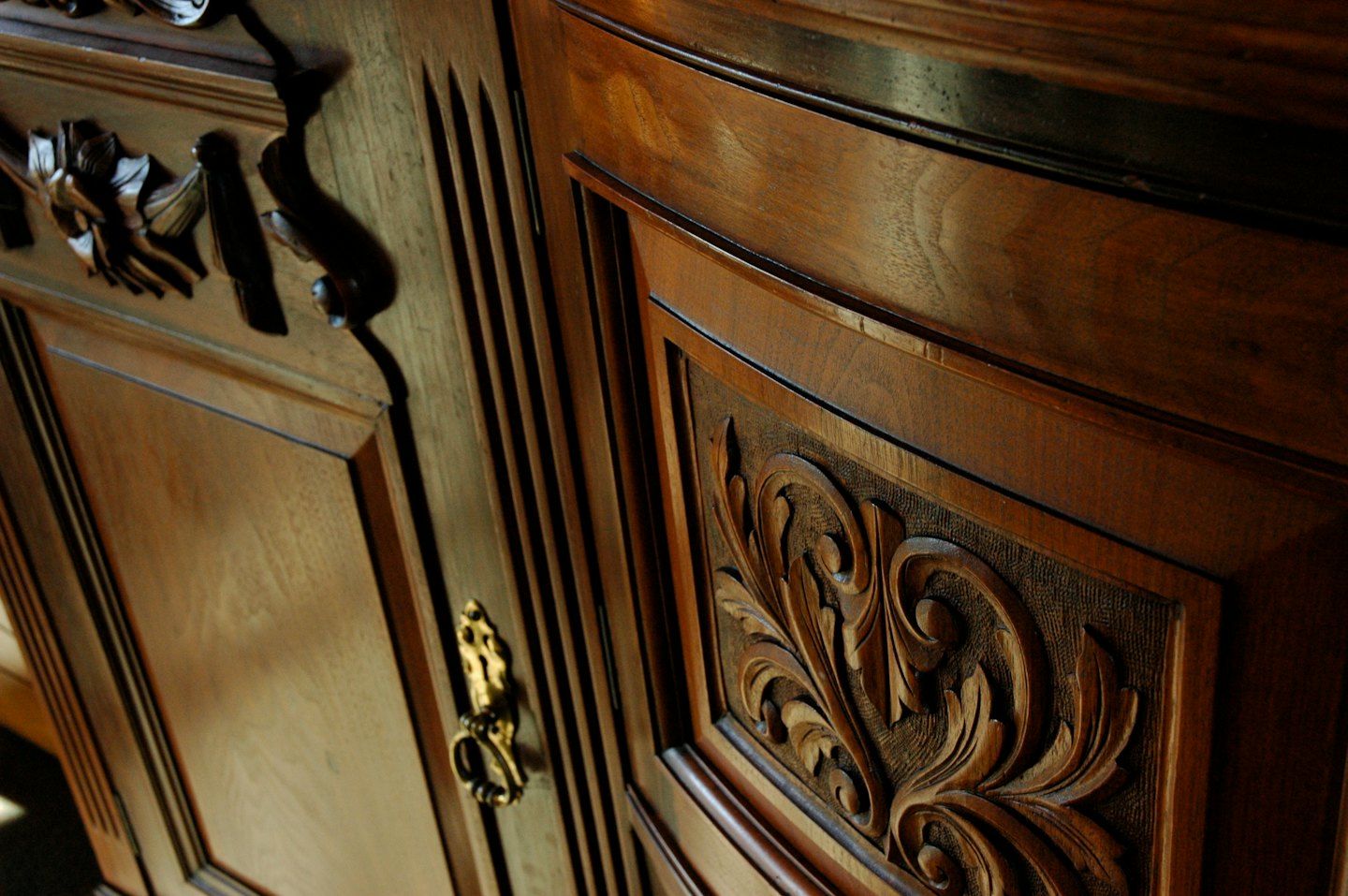Intricate carvings on a polished wooden cabinet with brass hardware.