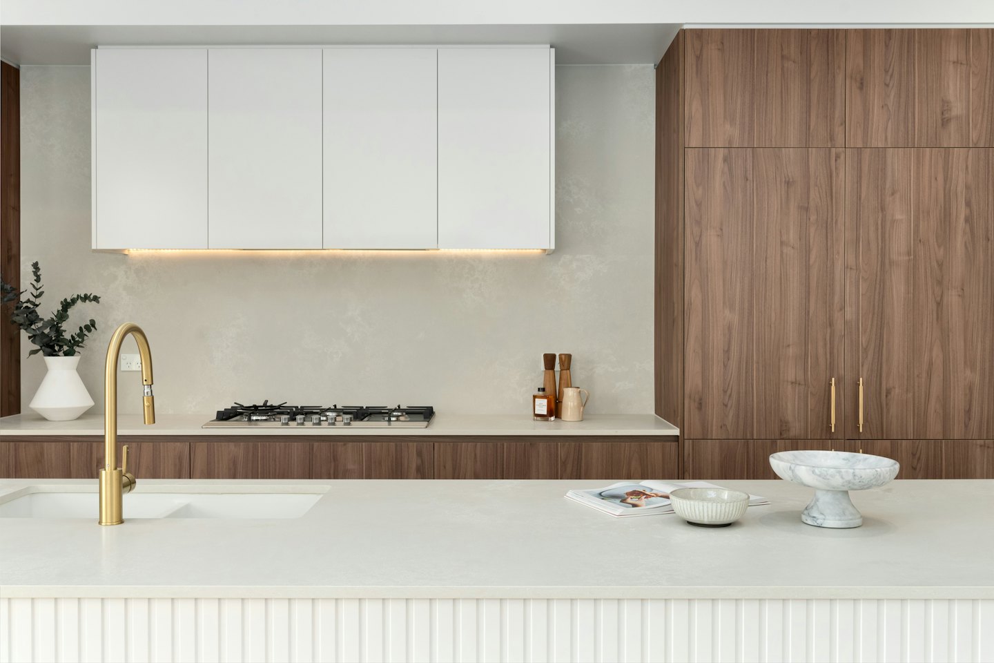 Modern kitchen with white and dark wood cabinets and gold faucet.