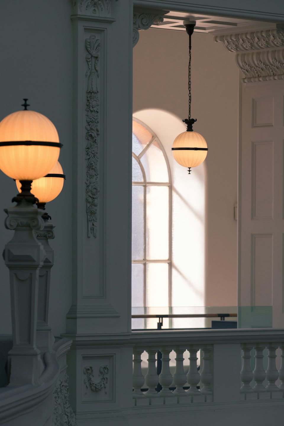 Interior with white balustrades, columns, and arched window.